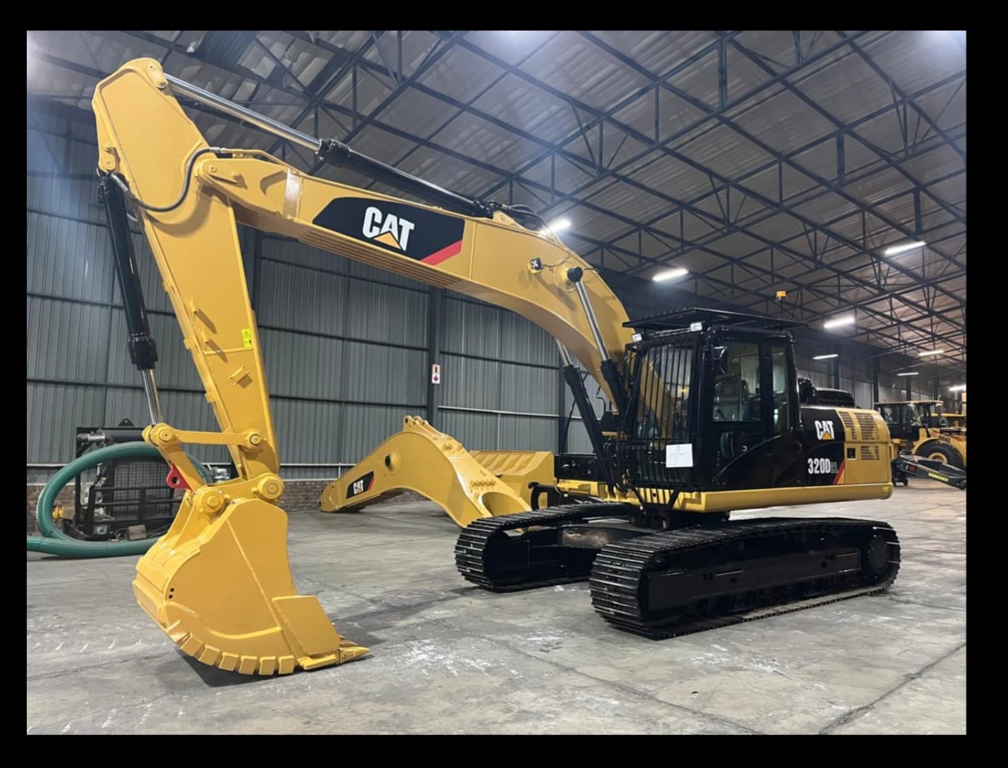Caterpillar 320D excavator with spare bucket in the equipment warehouse