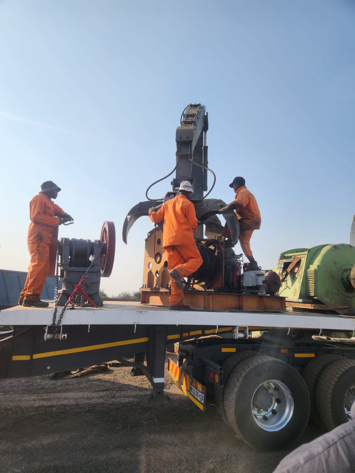 Rigging crew loading crusher plant components onto a trailer