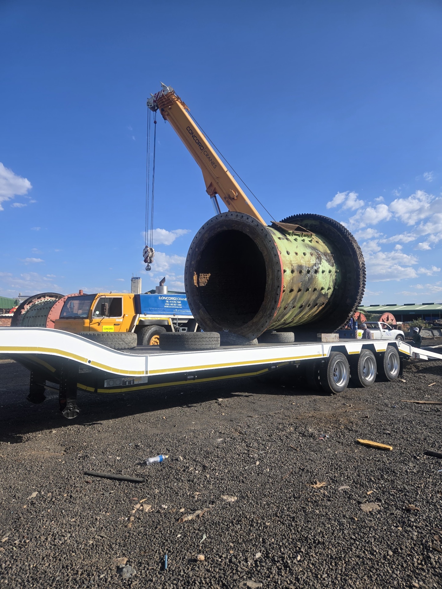 Mobile crane loading a ball mill onto a low-bed trailer